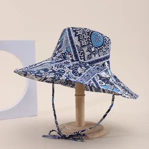 Detailed macro shot of blue paisley wide-brim sun hat displayed on a wooden stand.