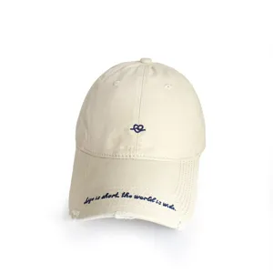 Detailed macro view of a vintage beige baseball cap with blue embroidery and distressed brim