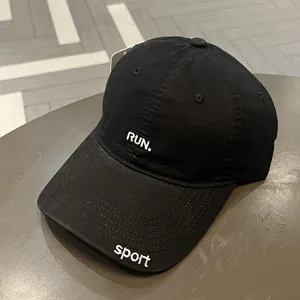 Dettaglio di un cappello da baseball nero in cotone con ricamo bianco RUN. e sport
