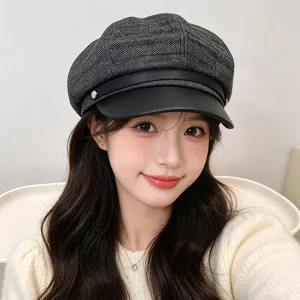 Close-up of a stylish grey newsboy cap with black leather brim worn by a model