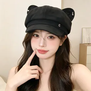 Close-up detail of stylish black newsboy cap with cute cat ears, pearl accents and metal logo.
