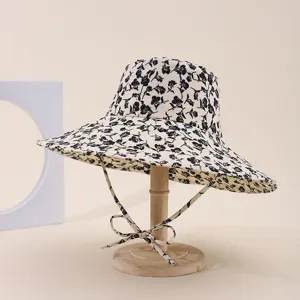 Elegant floral print sun hat featuring a wide brim and chin strap on a wooden stand