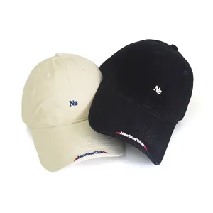 Detail view of casual embroidered letter baseball cap in beige and black, fine stitching.