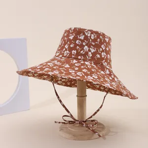 Detailed view of a brown floral print wide-brim sun hat on a wooden display stand.