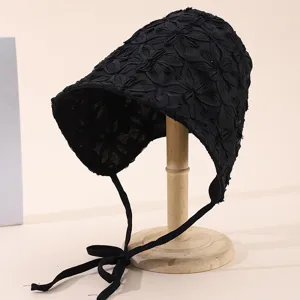 Chapeau de soleil noir avec texture florale et liens, protection estivale élégante.