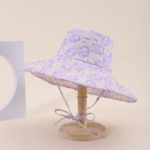 Detailed view of the wide-brim sun hat featuring a vibrant purple floral print and chin strap.