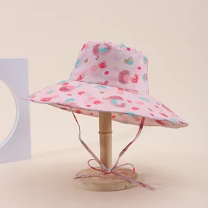 Pink wide-brim sun hat featuring colorful abstract dots on a wooden display stand.