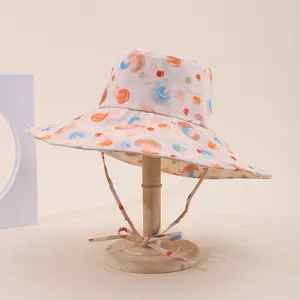 Wide-brimmed sun hat with colorful abstract print, chin strap, and wooden stand detail