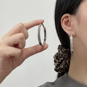 Detail of sparkling silver hoop earrings with crystals worn by a stylish model