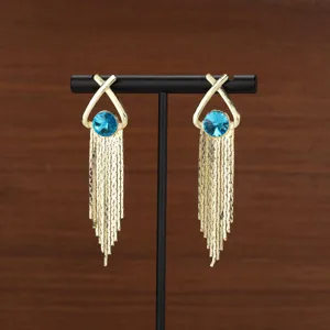 Detailed macro view of elegant gold fringe tassel earrings with a vibrant blue crystal