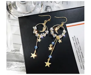 Gros plan détaillé de boucles d'oreilles pendantes asymétriques étoile et lune sur fond noir
