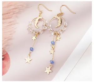 Vue détaillée de boucles d'oreilles asymétriques dorées étoile lune avec accents en cristal bleu