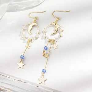 Elégantes boucles d'oreilles asymétriques en or avec étoile, lune et cristaux brillants.