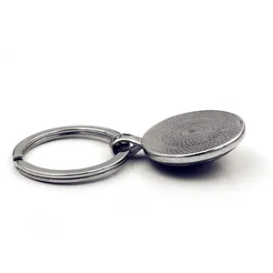 Detailopname van een zilveren metalen sleutelhanger met ronde getextureerde basis
