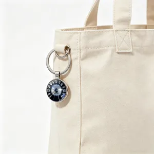 Detailed close-up of a vintage car speedometer keychain pendant hanging on a canvas bag