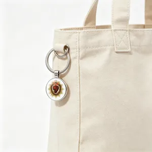 Detail of Sacred Heart glass cabochon keychain hanging on a beige canvas tote bag charm
