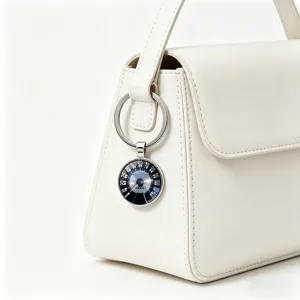 Close-up of vintage car speedometer keychain hanging on a white handbag