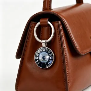 Close-up detail of a vintage car speedometer keychain hanging on a brown leather bag