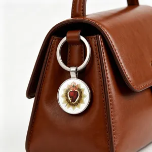 High-quality macro shot of a Sacred Heart metal keychain on a brown leather handbag