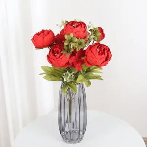 Detailed view of artificial red peony flower bouquet in a modern grey glass vase for home decor.