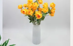 Détail de pivoines artificielles jaunes à 6 têtes dans un vase gris texturé.