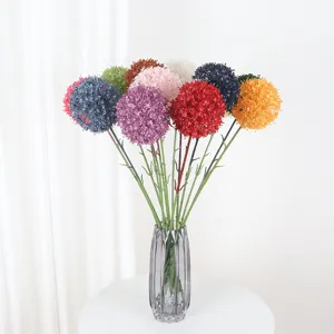 Kleurrijk kunstmatige allium bloemenboeket in glazen vaas voor bruiloft en woning.