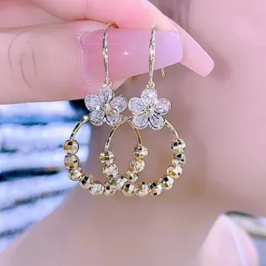 Detail shot of gold-finish flower earrings with sparkling crystals and faceted beads.