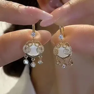 Close-up of elegant gold-tone vintage earrings with white opal and clear rhinestones.