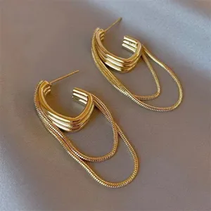 Detailed view of vintage gold C-shaped earrings with hanging snake chains on satin