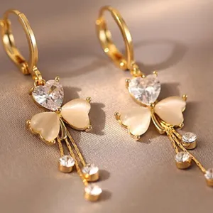 Detailed view of elegant gold-tone heart earrings with rhinestones and opal stones