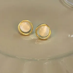 Close-up of elegant gold round stud earrings with milky white gemstone