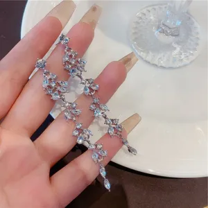 Close-up of elegant long dangle earrings with shimmering rhinestones in a vine design