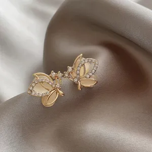 Macro view of elegant gold butterfly stud earrings inlaid with opal and crystals