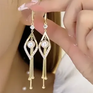 Detailed close-up of elegant gold geometric pearl earrings with long delicate fringe tassels
