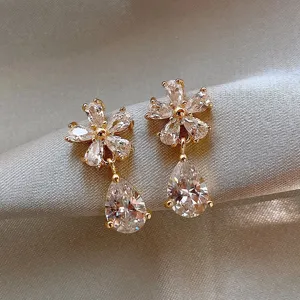 Macro view of elegant flower-shaped earrings with shimmering teardrop crystals on satin
