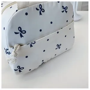 Primer plano detallado del bolso cosmético blanco con lazos azules y lunares elegantes.