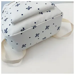 Detalle de mochila blanca con lunares azul marino y lazos bonitos con correas resistentes.
