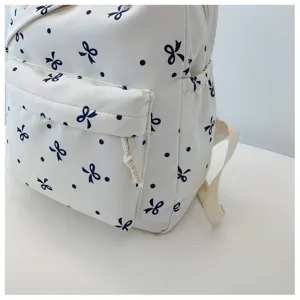 Vista detallada de una mochila casual blanca con lindo patrón de lazos y lunares azul oscuro.