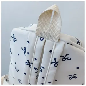 Vista detallada de la mochila de lona informal con estampado de lazos azules y fuertes correas.