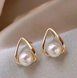 Close-up detail of elegant gold teardrop stud earrings with a lustrous white pearl center