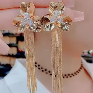 Detailansicht eleganter goldfarbener Blumenohrringe mit Zirkonia und langen Quasten.