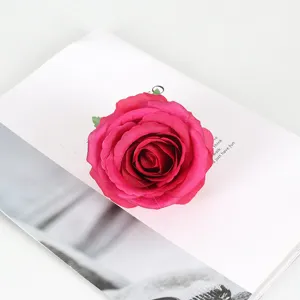 Gros plan détaillé d'une tête de rose artificielle magenta vive sur un accessoire de livre.
