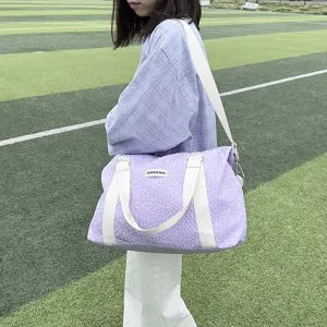 Detailed view of the stylish purple quilted yoga travel bag worn on shoulder outdoors.