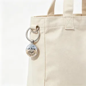 Detail shot of an inspirational Bible verse keychain attached to a cream canvas tote bag.