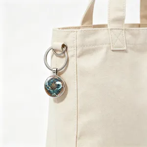 Close-up detail of vintage nautical compass keychain hanging on a beige canvas tote bag