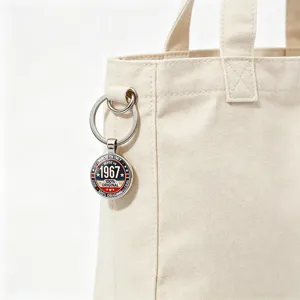 Close-up of vintage 1967 metal keychain hanging on a beige canvas tote bag.