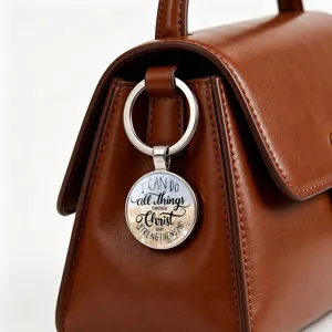 Detailed view of an inspirational Bible verse keychain attached to a brown leather bag.