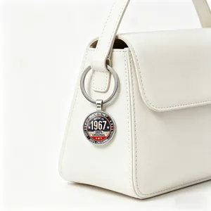 Retro 1967 metal keychain hanging on a white handbag for a stylish vintage look.