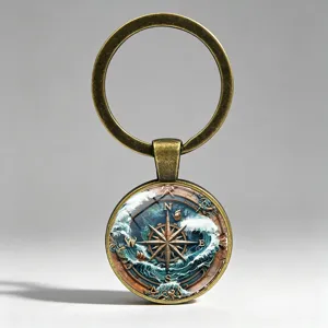 Close-up of vintage nautical compass keychain with sailing boat and sea waves glass gem.