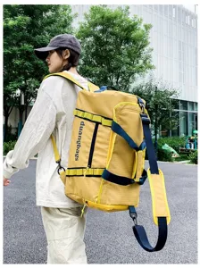 Large capacity yellow grid pattern travel duffel bag carried by model in outdoor setting
